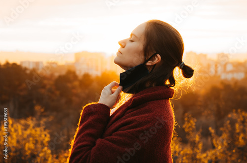 Photography Side view of young woman taking the face mask off for a gulp of fresh air backli