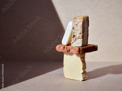 empilement de savons artisanaux pour le corps ou les mains, soins d'hygiène écologiques sur un fond neutre baigné de soleil