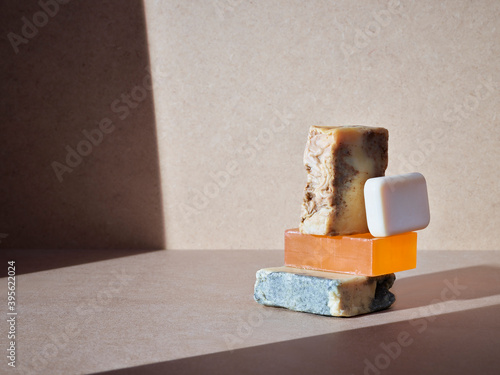 empilement de savons artisanaux pour le corps ou les mains, soins d'hygiène écologiques sur un fond neutre baigné de soleil