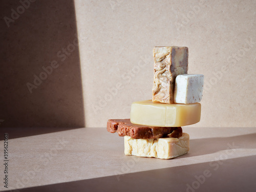 empilement de savons artisanaux pour le corps ou les mains, soins d'hygiène écologiques sur un fond neutre baigné de soleil