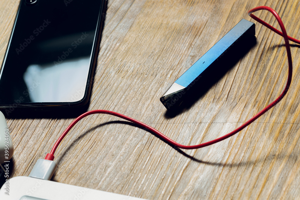 Computer Vapes POD e-cigarette or nicotine vapor dispenser being charged in modern ...