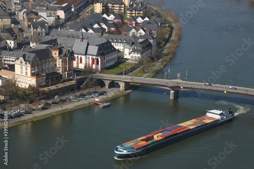 Inland cargo ship with colorful container freight passing a bridge in the historic old town of Bernkastel-Kues on the Mosel river in Germany