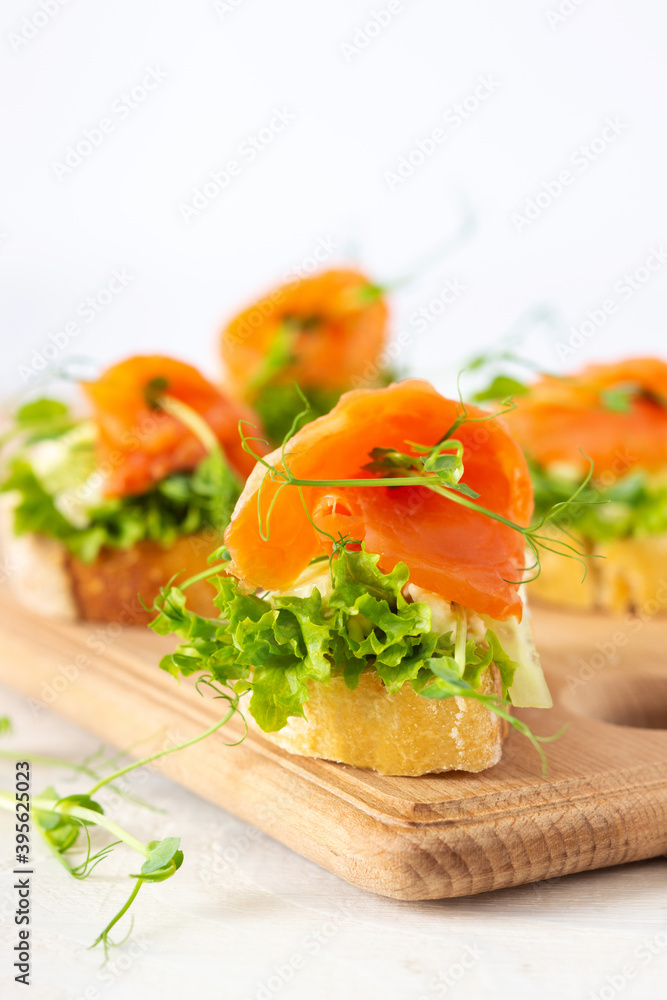 Canapes with mozzarella cheese, salad, salmon and pea sprouts, toast with red fish on a wooden board close up Canapes with mozzarella cheese, salad, salmon and pea sprouts, toast with red fish on a wooden board close up