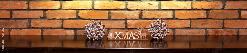 Naklejka premium Xmas inscription and Christmas decorations on the background of an old brick wall.