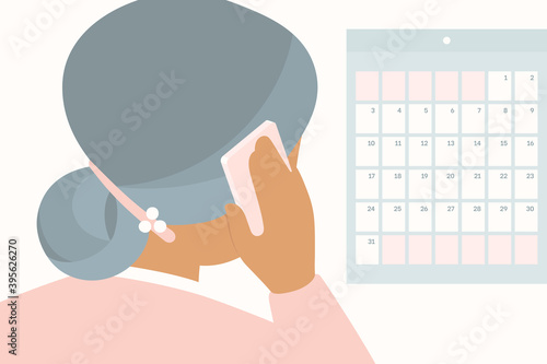 Elderly woman scheduling an appointment over the phone while looking at calendar