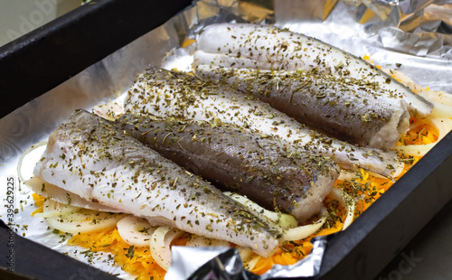 Photography five raw fish with spices and vegetables on foil, prepared for baking