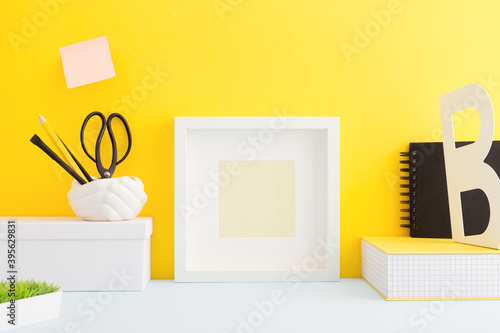 Table with frame, school supplies and yellow wall. photo