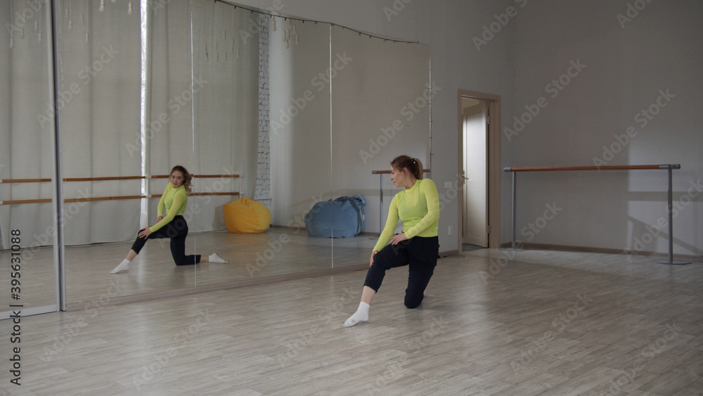 Obraz premium Jump with split of a beautiful girl contemporary dancer. Spacious Studio with a large mirror in the dance school. Training with a warm-up.