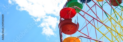 Vintage old fashioned bright multicolored Ferris wheel against a blue cloudy sky. Copy space. Banner.	