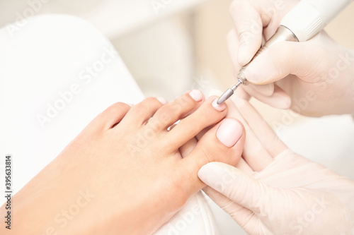 Beautiful salon procedure with pink pedicure on towel background. For decoration design. Healthcare. Woman body care. Spa treatment. White background. Nail machine polish. Medical