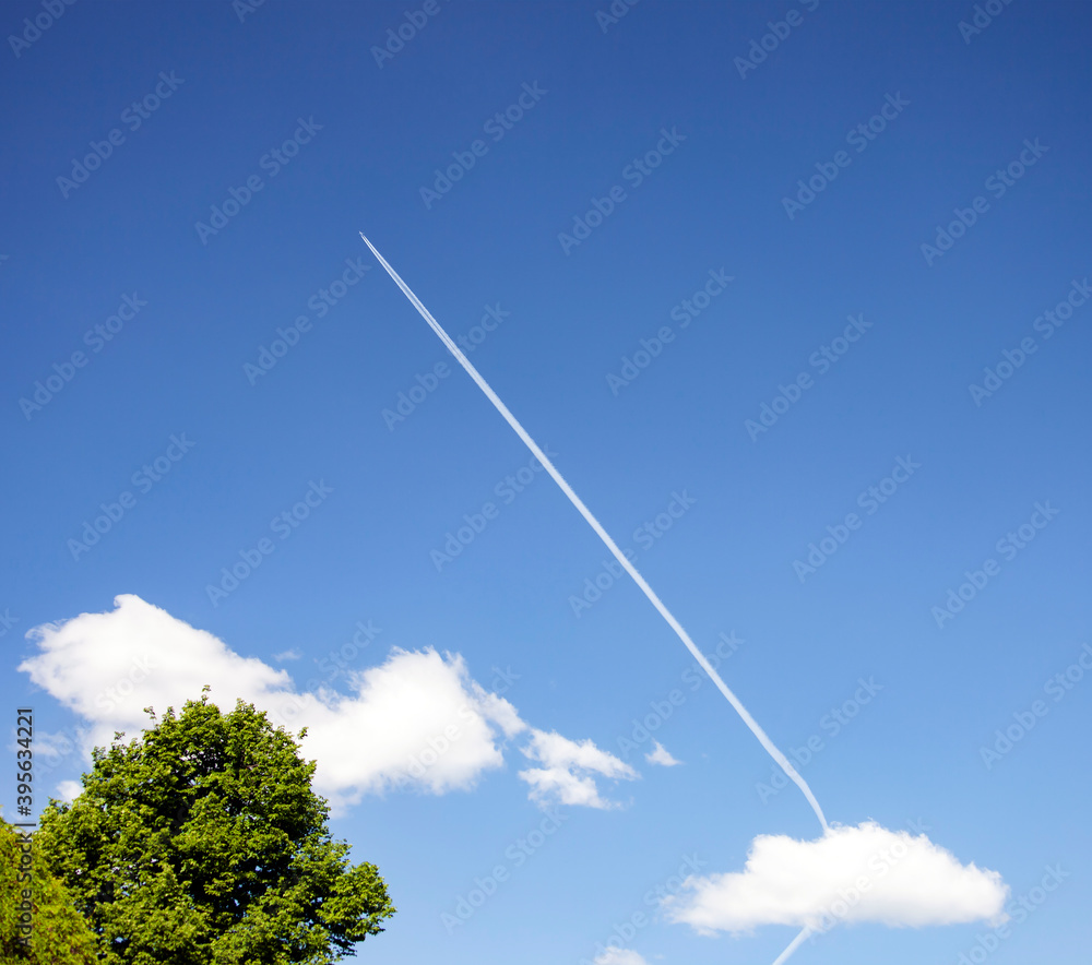 White contrail from the plane's turbines in the blue sky.