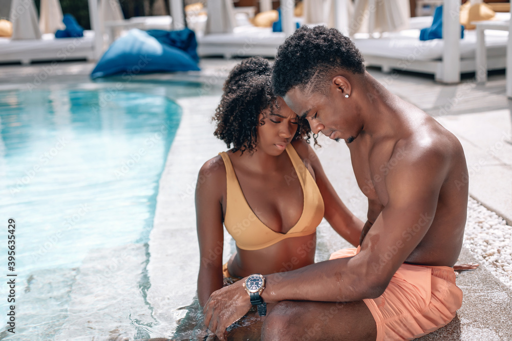 Soft focus portrait of a loving African American couple sitting near the swimming pool and kissing. Phuket. Thailand. Trip to warm destination