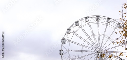 Modern white Ferris wheel in the central park against sky. Entertainment, attraction, amusement park, minimal concept. Banner.