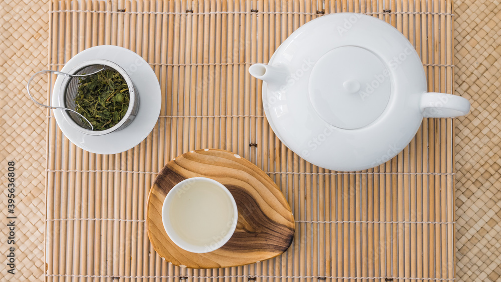 Tea set top view. Porcelain teapot, teacup and green tea in a metal filter on a bambou tray. Beautiful professional shot of the teaware. Morning breakfast. Tea set top view. Porcelain teapot, teacup and green tea in a metal filter on a bambou tray. Beautiful professional shot of the teaware. Morning breakfast.