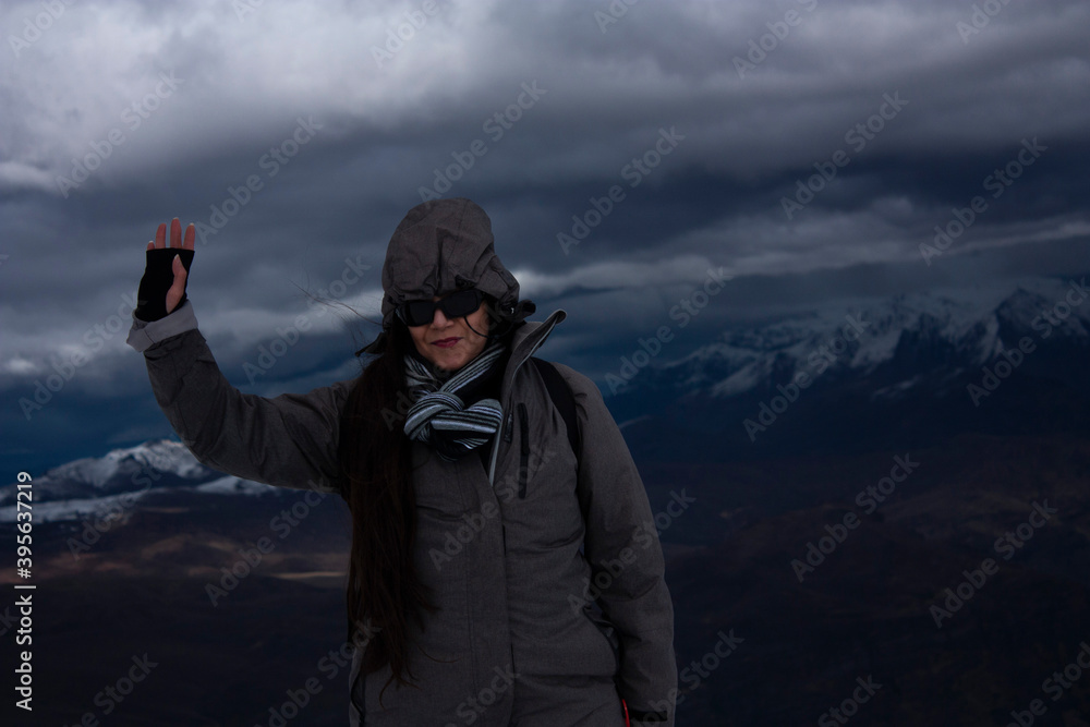 Woman living the experience in the mountains wearing winter clothes .jacket scarf and sunglasses in winter Christmas atmosphere
