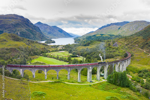 Classic Steam Train travelling across an old bridge with dramatic landscape in the background in Scotland 