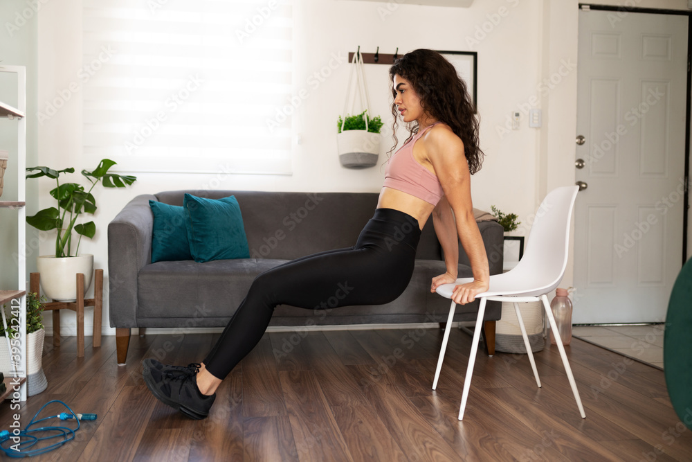 Beautiful woman doing tricep dips with a chair at home Beautiful woman doing tricep dips with a chair at home