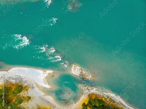 Top view of a wide blue beautiful river with foam and ice. Forest on the right side of the photo