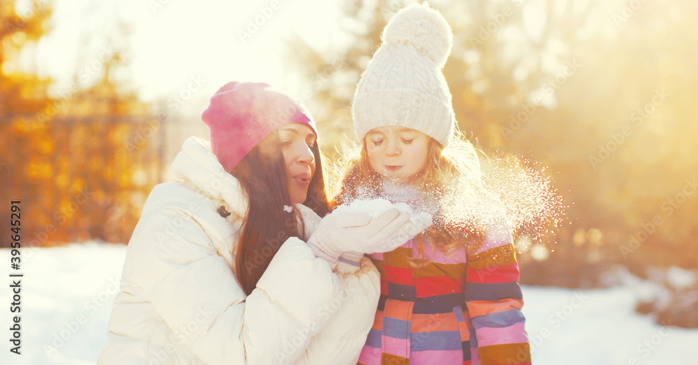 Portrait of happy mother and little girl child playing in winter over snowy background Portrait of happy mother and little girl child playing in winter over snowy background