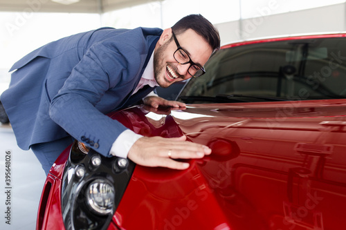 Young handsome man choosing a new car at car showroom. © hedgehog94