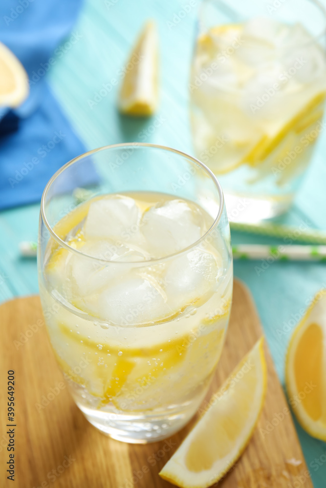 Soda water with lemon slices and ice cubes on light blue wooden table