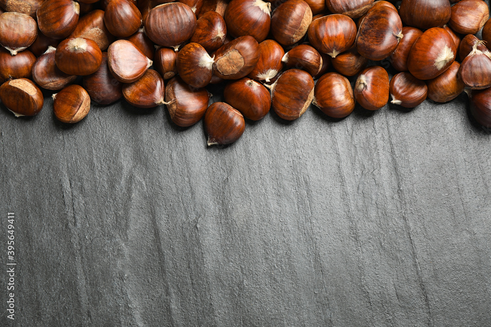 Fresh sweet edible chestnuts on black slate table, flat lay. Space for text Fresh sweet edible chestnuts on black slate table, flat lay. Space for text