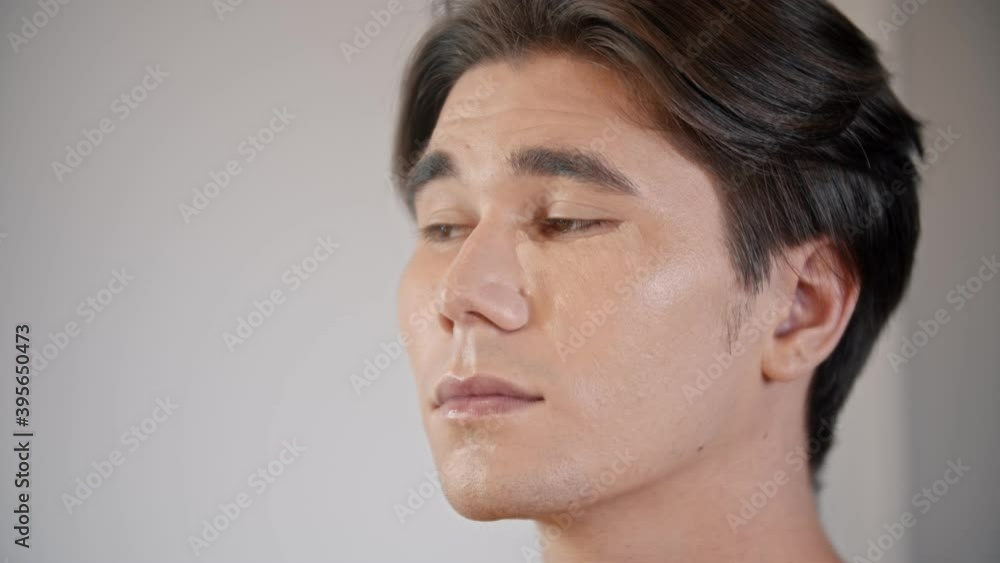 Woman make up artist applying concealer under the eyes of male model using a brush Woman make up artist applying concealer under the eyes of male model using a brush