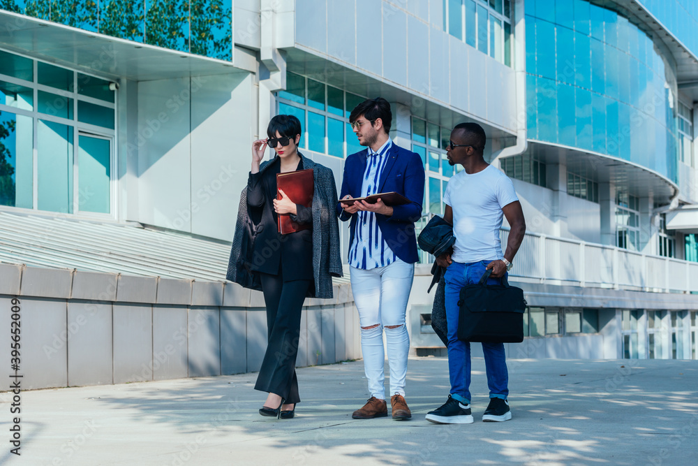 Obraz premium Businessman showing documents to his multi-ethnic co-workers in front of their big modern office building