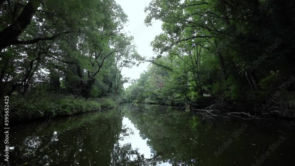 Sailing through a calm, deep river, located between two mainlands filled with green trees on a cloudy day. Sailing through a calm, deep river, located between two mainlands filled with green trees on a cloudy day.