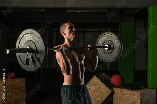 Muscular man working out with a barbell at his homemade gym