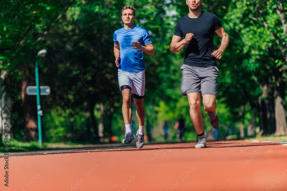 Obraz premium Two healthy young men running in the park on a sunny day..