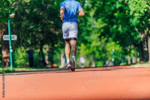 Close up feet with running shoes and strong athletic legs of sport man jogging on the running track