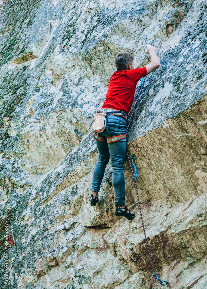 Male rock climber climbing along a roof in a cliff