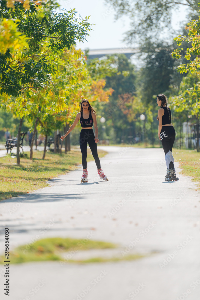 Obraz premium Full-length picture of sexy sportswomen rollerskating in the park