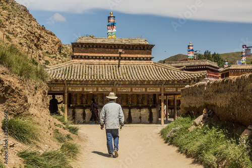 XIAHE, CHINA - AUGUST 24, 2018: People walk at the Inner Kora (pilgrim path) around Labrang Monastery in Xiahe town, Gansu province, China photo