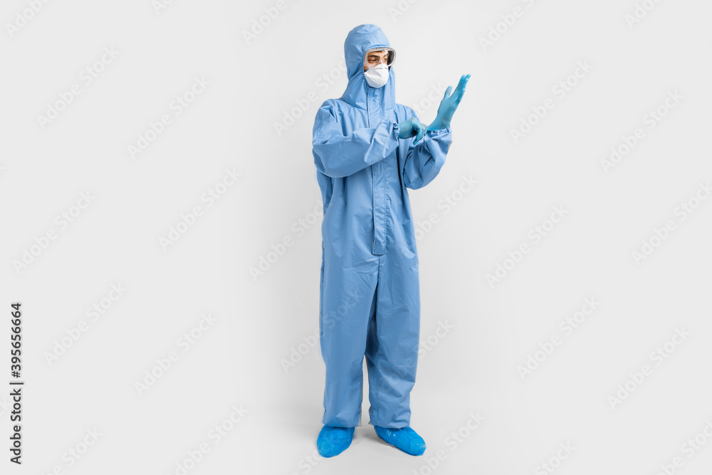 Full-length male doctor in protective clothing, glasses, mask and gloves, on a white background, coronavirus epidemic concept