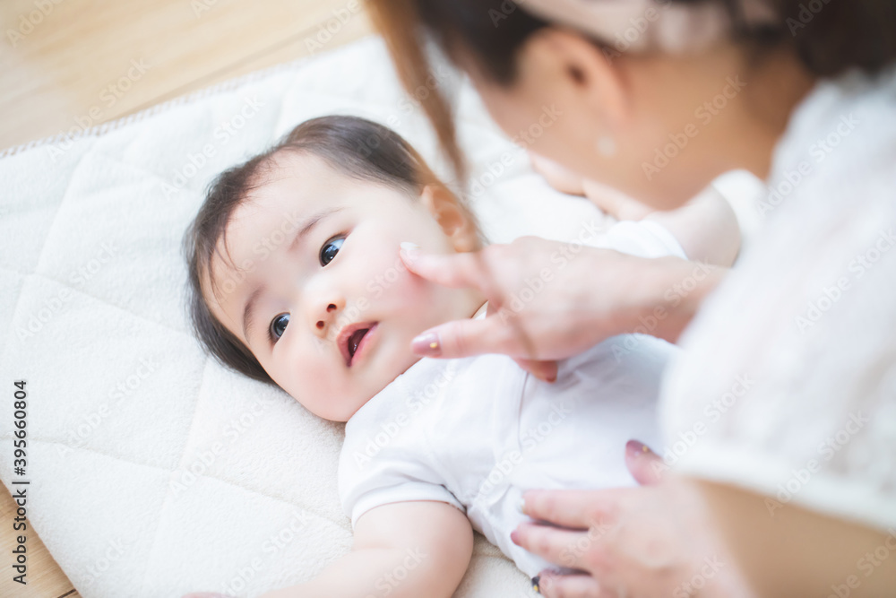 赤ちゃんを床に寝かせる女性
赤ちゃんを床に寝かせる女性