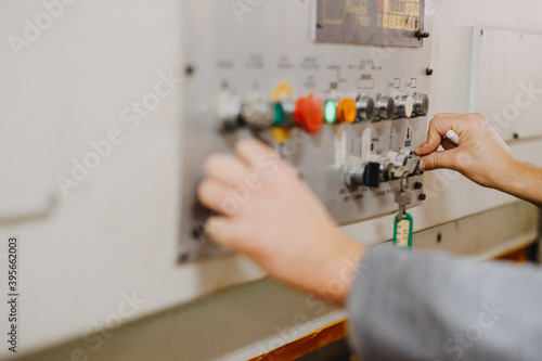Tableau sur toile Closeup shot of hands operating colorful knobs and buttons on an industrial mach