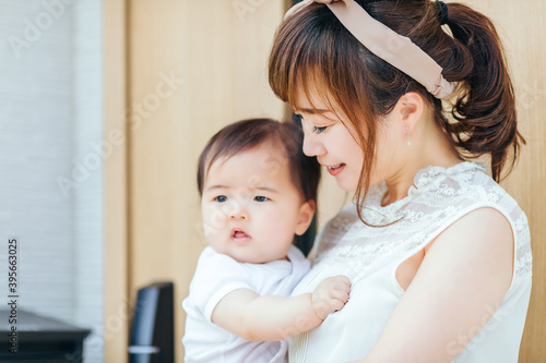 マイホームの前で赤ちゃんを抱く若い女性 