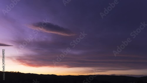 Dark purple and blue clouds glow with sunset light in sky, Timelapse photo