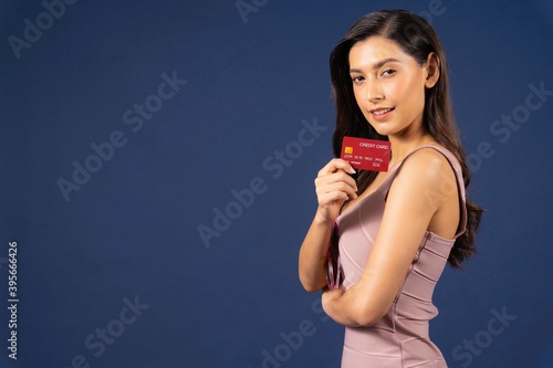 Young asian woman holding and presenting credit card for online shopping on blue color background, Shopping online concept, Cashless payment, black friday