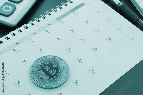 Bitcoins operations concept, bitcoin coin on calendar with calculator.