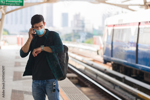 Caucasian man wearing surgical masks waiting to board the public train at rush hour.