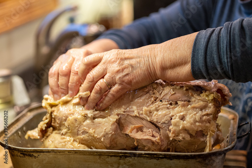 Woman uses her hands to de-bone a Thanksgiving turkey, removing the meat from bones. Selective focus, on one hand