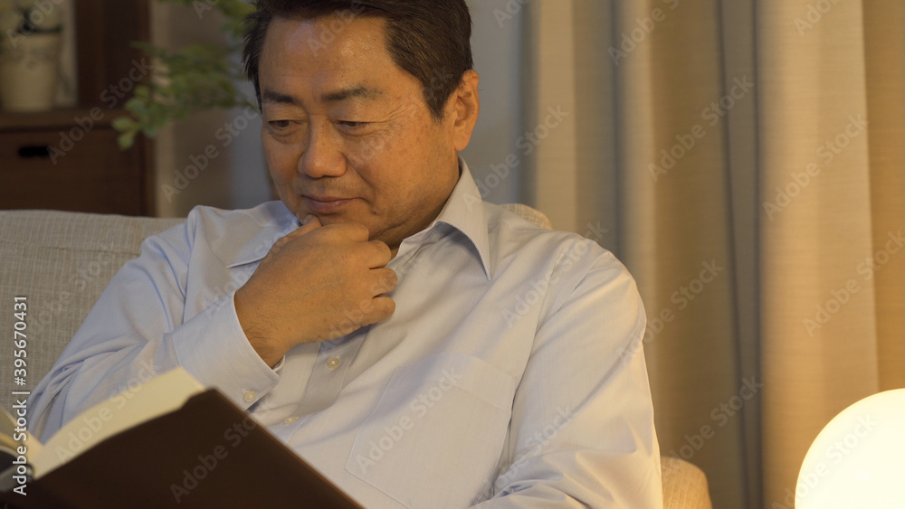 Fototapeta premium 夜間に読書をする中高年男性