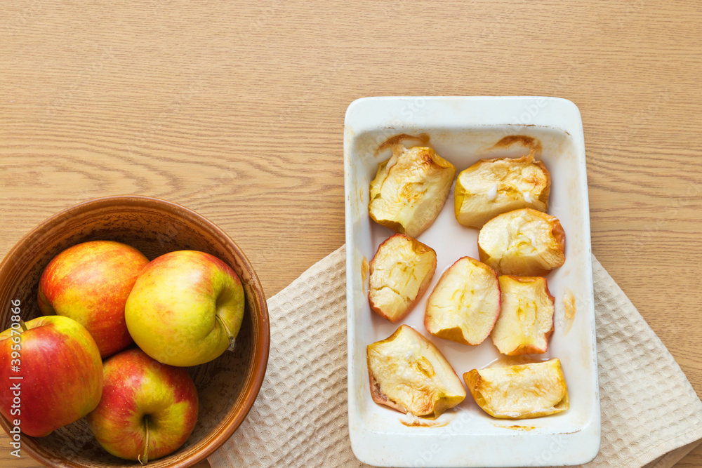 Freshly baked sweet apples in ceramic form on a wooden table. Delicious organic sweets rich in fiber. Digestible food for elderly people, children and people with health problems. Flat lay, copy space