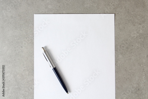 Template of white paper with a ballpoint pen on light grey concrete background. Concept of new idea, business plan and strategy, empty space for text