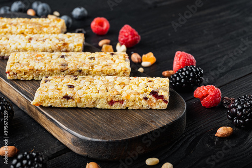Superfood breakfast bars with oats nuts and berries with copy space, on black wooden table