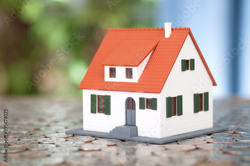 House model placed on a background covered with dollar coins