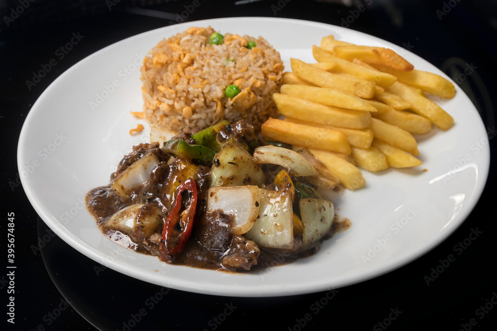 Beef in black bean sauce served with fried rice and French fries Beef in black bean sauce served with fried rice and French fries